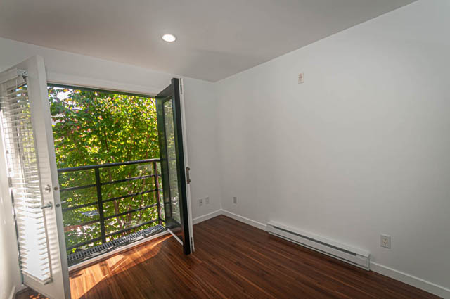 Bright living room with hardwood floors and a view of greenery outside. - 2753 Guelph Street, Vancouver East Side