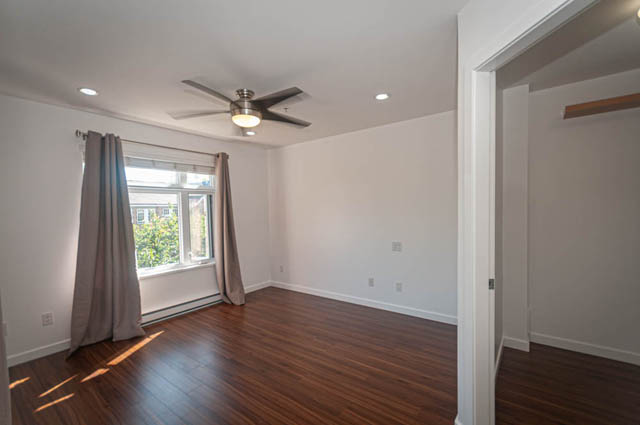 Bright living room with hardwood floors and a ceiling fan, natural light from the window. - 2753 Guelph Street, Vancouver East Side