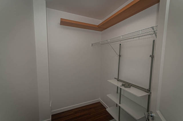 Bright walk-in closet with white walls, wooden beams, and a metal shelving unit. - 2753 Guelph Street, Vancouver East Side