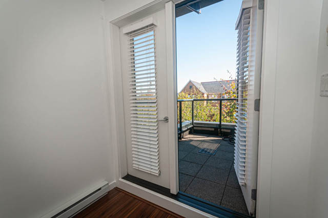 Bright sunroom with white blinds, hardwood floors, and a view of the balcony and rooftops. - 2753 Guelph Street, Vancouver East Side