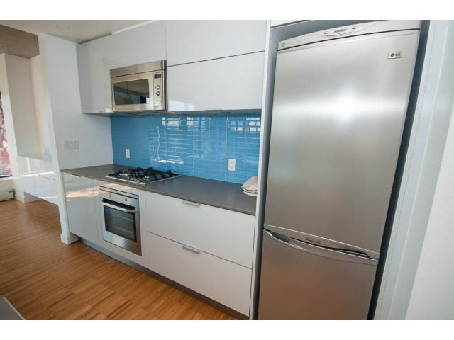 Bright kitchen with modern stainless steel appliances, blue backsplash, and hardwood floors. - 803 - 128 Cordova St W, Vancouver Downtown