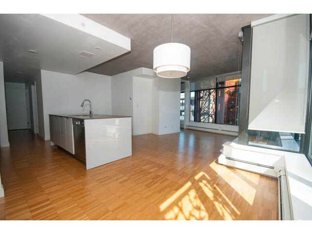 Spacious living room with hardwood floors, modern light fixture, and city view. - 803 - 128 Cordova St W, Vancouver Downtown
