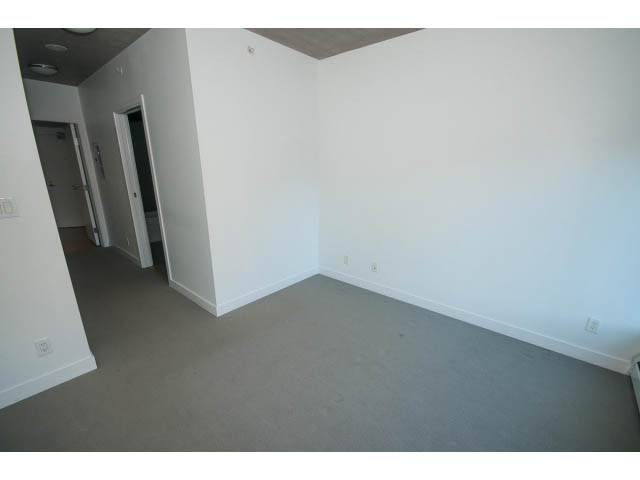 Bright living room with neutral carpet and white walls, door leading to another room. - 803 - 128 Cordova St W, Vancouver Downtown