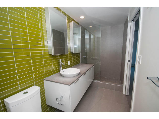 Bright bathroom with green tile walls, modern sink, and large mirror. - 803 - 128 Cordova St W, Vancouver Downtown