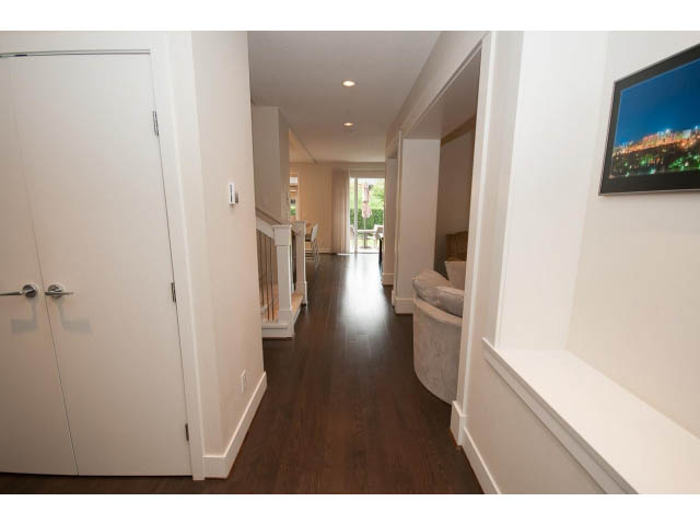 Foyer with dark hardwood floors and white walls, leading to a bright living area. - 26 - 555 Raven Woods Drive, North Vancouver