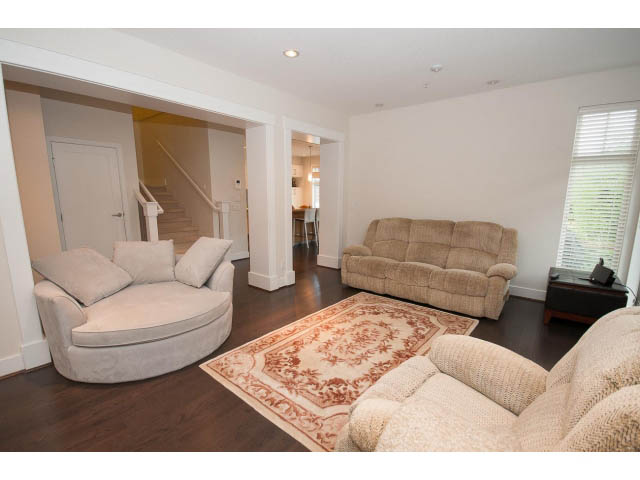 Spacious living room with hardwood floors, plush furniture, and a large window. - 26 - 555 Raven Woods Drive, North Vancouver