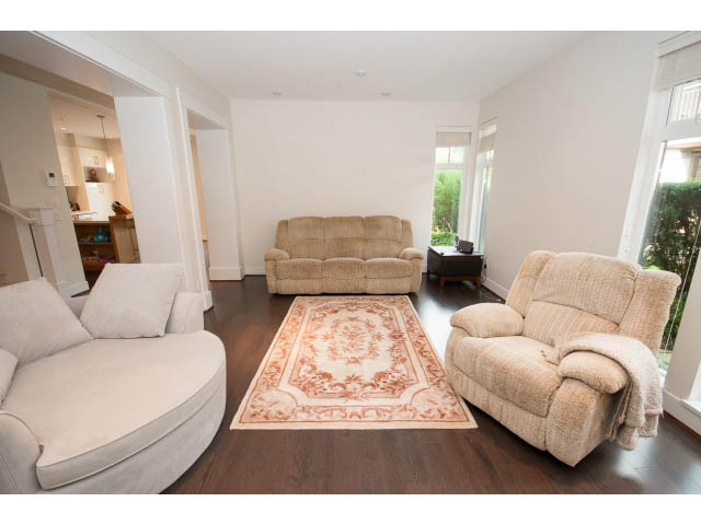 Bright living room with hardwood floors, large windows, and a patterned rug. - 26 - 555 Raven Woods Drive, North Vancouver