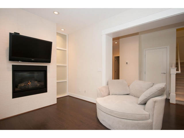 Spacious living room with modern fireplace and large TV, hardwood floors. - 26 - 555 Raven Woods Drive, North Vancouver