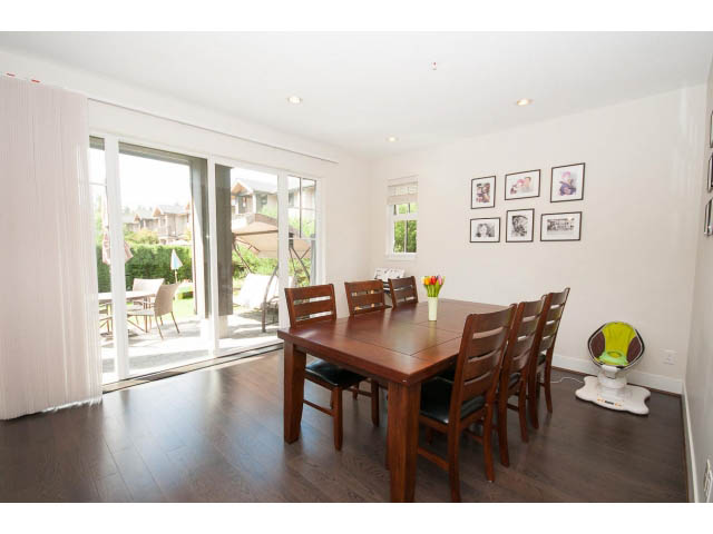 Spacious dining area with hardwood floors, large windows, and wall art. - 26 - 555 Raven Woods Drive, North Vancouver