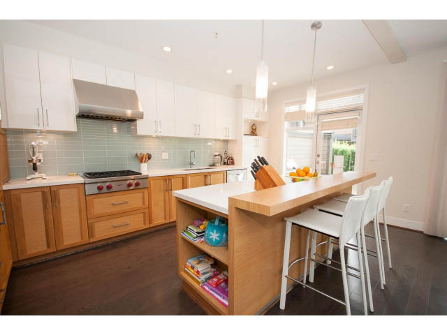 Bright kitchen with white cabinets, hardwood floors, and a view of the outdoors. - 26 - 555 Raven Woods Drive, North Vancouver