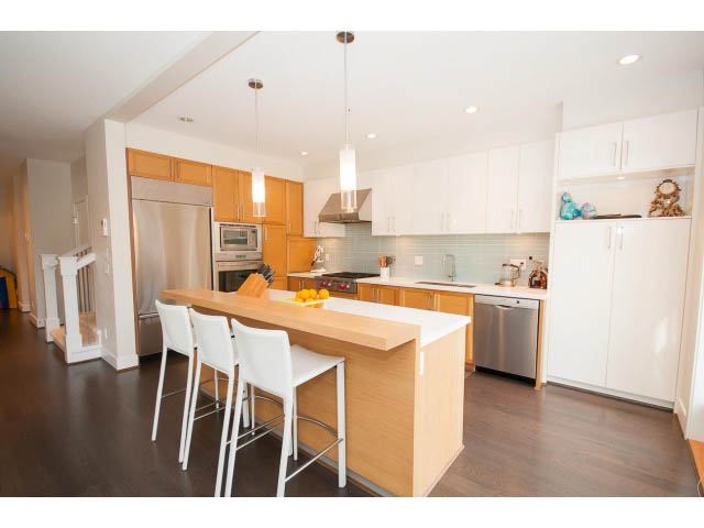 Bright kitchen with wooden cabinets, stainless steel appliances, and hardwood floors. - 26 - 555 Raven Woods Drive, North Vancouver