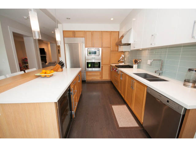 Bright kitchen with white countertops, hardwood floors, and stainless steel appliances. - 26 - 555 Raven Woods Drive, North Vancouver