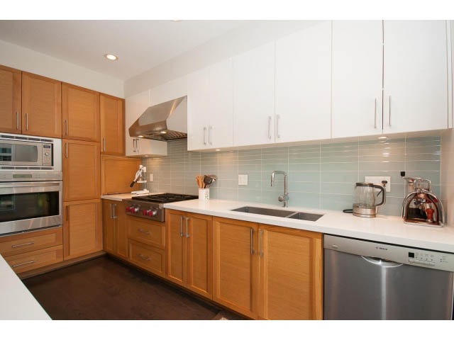 Bright kitchen with white cabinets, stainless steel appliances, and light blue backsplash. - 26 - 555 Raven Woods Drive, North Vancouver