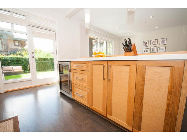 Bright kitchen with wooden cabinets, hardwood floors, and a city view through sliding glass doors. - 26 - 555 Raven Woods Drive, North Vancouver