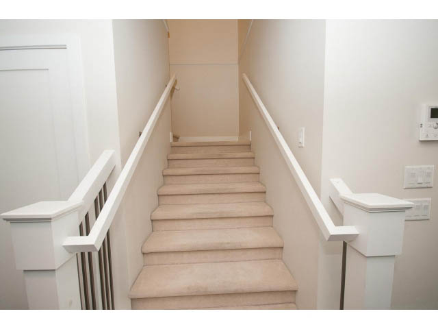 Staircase leading to upper level with white railings and light-colored steps. - 26 - 555 Raven Woods Drive, North Vancouver