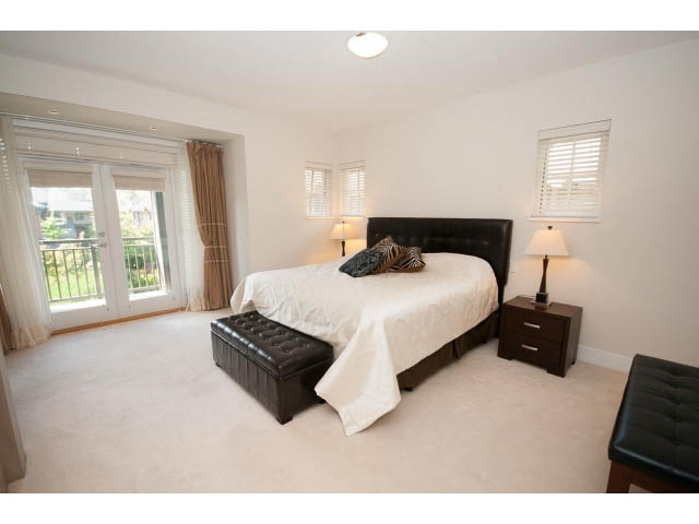 Spacious bedroom with large windows, cozy bedding, and a view of the outdoors. - 26 - 555 Raven Woods Drive, North Vancouver
