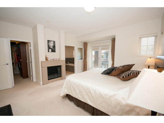 Spacious bedroom with large bed, zebra print pillows, and closet access. - 26 - 555 Raven Woods Drive, North Vancouver