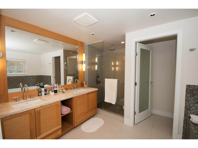 Spacious bathroom with wooden cabinets, large mirror, and walk-in shower. - 26 - 555 Raven Woods Drive, North Vancouver