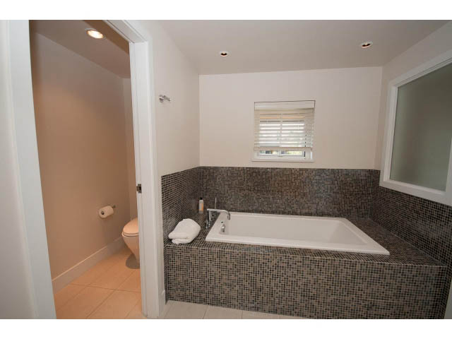 Spacious bathroom with mosaic tile walls and a large bathtub. - 26 - 555 Raven Woods Drive, North Vancouver