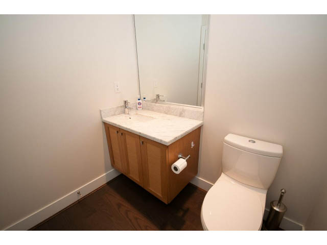 Bright bathroom with white countertop, wooden cabinets, and hardwood floors. - 26 - 555 Raven Woods Drive, North Vancouver
