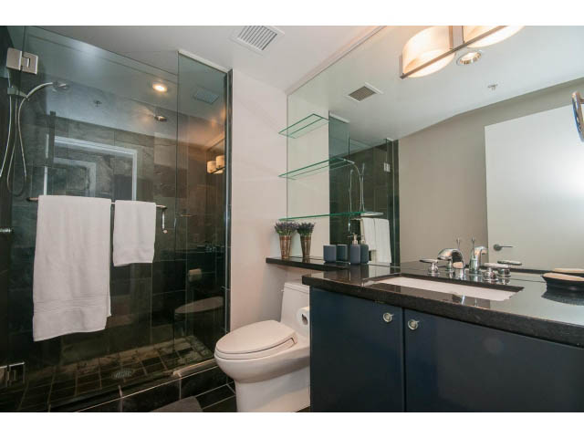 Modern bathroom with glass shower, dark countertops, and sleek fixtures. - 1702 - 1281 W. Cordova Street, Vancouver Downtown