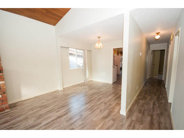 Bright living room with hardwood floors and a brick accent wall. - 1730 Bowser Ave., North Vancouver