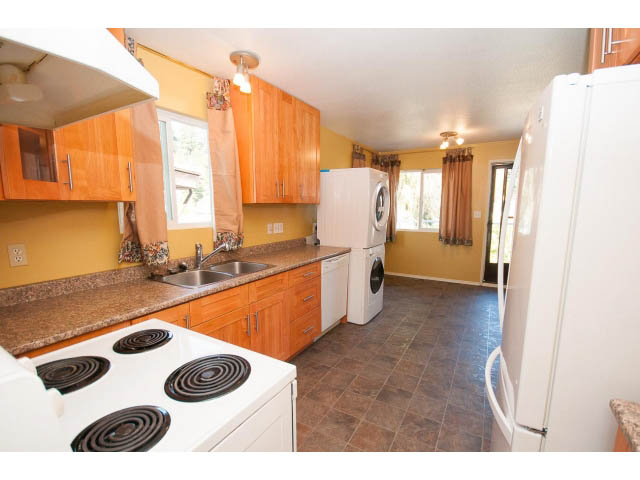 Bright kitchen with yellow walls, granite countertops, and a view of the laundry area. - 1730 Bowser Ave., North Vancouver