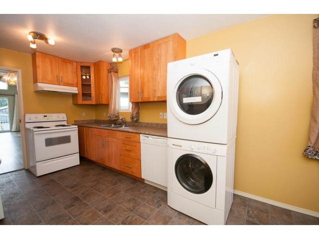 Shared laundry room with white appliances and wooden cabinets. - 1730 Bowser Ave., North Vancouver