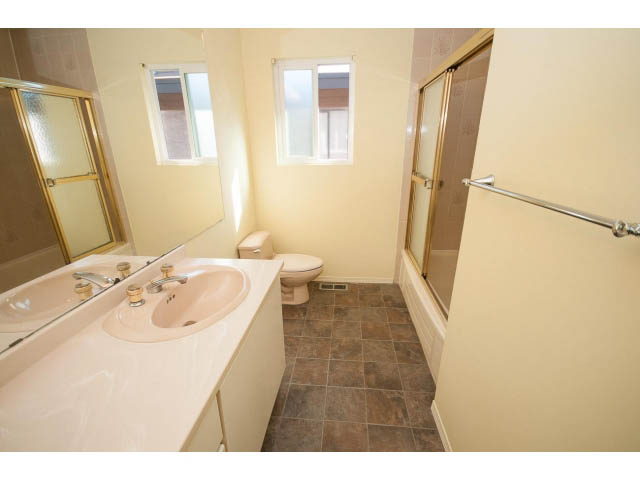 Bright bathroom with white vanity, tiled floor, and sliding glass shower door. - 1730 Bowser Ave., North Vancouver