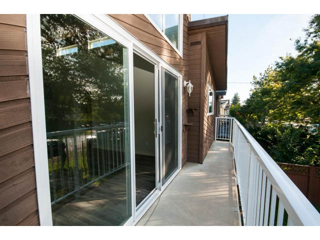 Bright balcony with sliding glass doors and wooden deck, offering a serene outdoor space. - 1730 Bowser Ave., North Vancouver