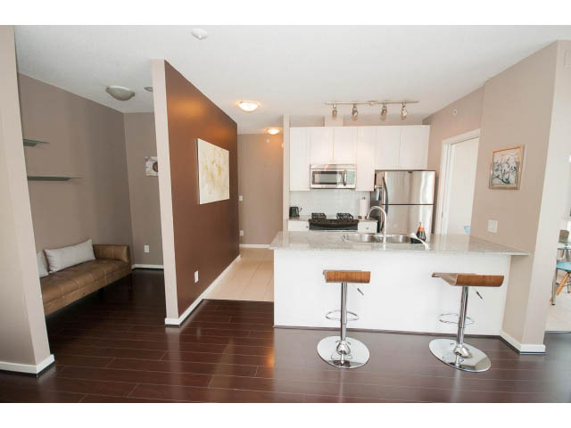 Bright kitchen with white cabinets, stainless steel appliances, and dark hardwood floors. - 1202 - 480 Robson Street, Vancouver Downtown