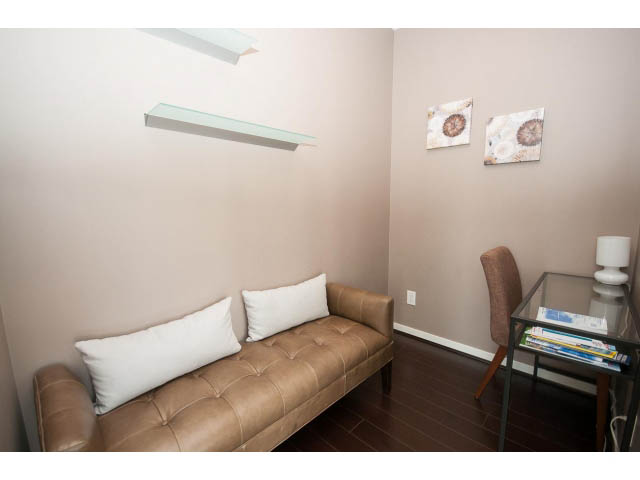 Furnished living room with a tan leather couch, white pillows, and modern decor. - 1202 - 480 Robson Street, Vancouver Downtown