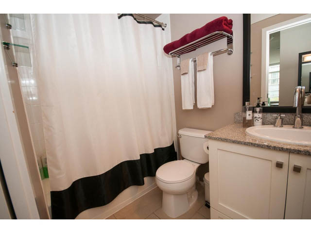 Bright bathroom with granite countertops and a shower curtain. - 1202 - 480 Robson Street, Vancouver Downtown