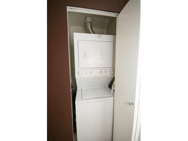 Laundry area with stacked washer and dryer, brown walls. - 1202 - 480 Robson Street, Vancouver Downtown