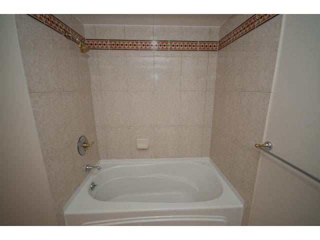 Bathroom with white tub, beige tiles, gold fixtures. - 707 - 1288 Marinaside Crescent, Vancouver Downtown