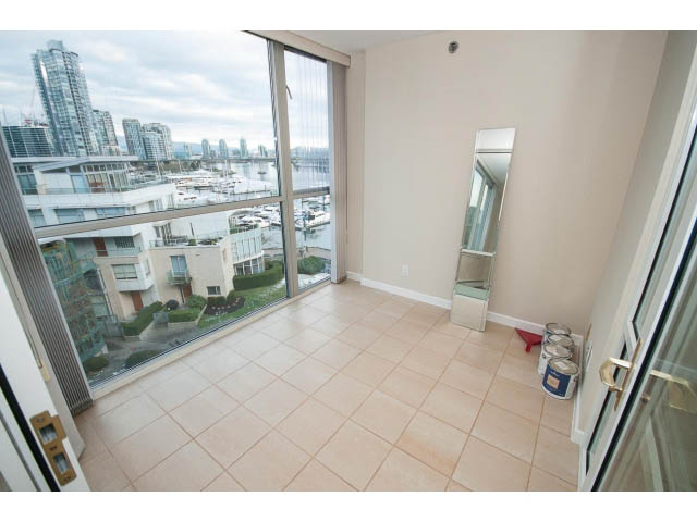 Bright living room with large windows offering a stunning city view, featuring tiled flooring and a modern mirror.