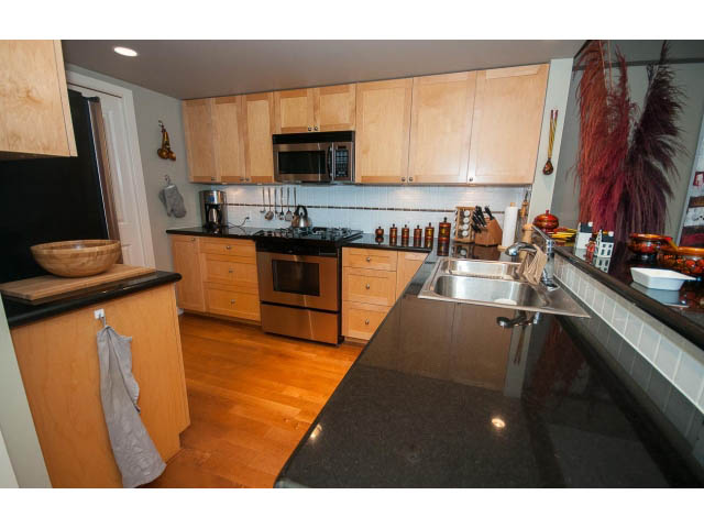 Bright kitchen with dark granite countertops, hardwood floors, and a modern microwave. - 603 - 1425 West 6th Ave, Vancouver West Side