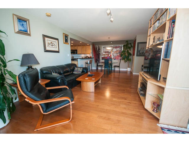 Bright living room with hardwood floors, modern furniture, and a kitchen in the background. - 603 - 1425 West 6th Ave, Vancouver West Side
