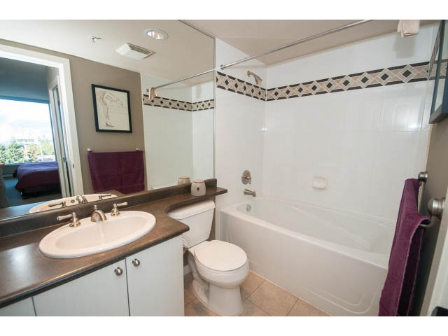 Furnished bathroom with modern sink, bathtub, and city view mirror. - 603 - 1425 West 6th Ave, Vancouver West Side