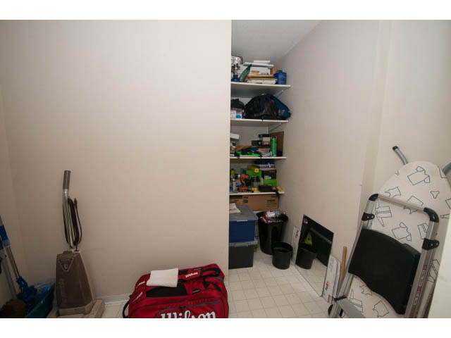 Storage closet with shelves and cleaning supplies, small table with items, and a red sports bag. - 603 - 1425 West 6th Ave, Vancouver West Side