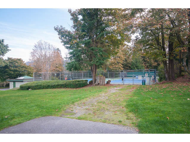 Fenced backyard with grass, trees, and a tennis court. - 389 Beachview Dr, North Vancouver