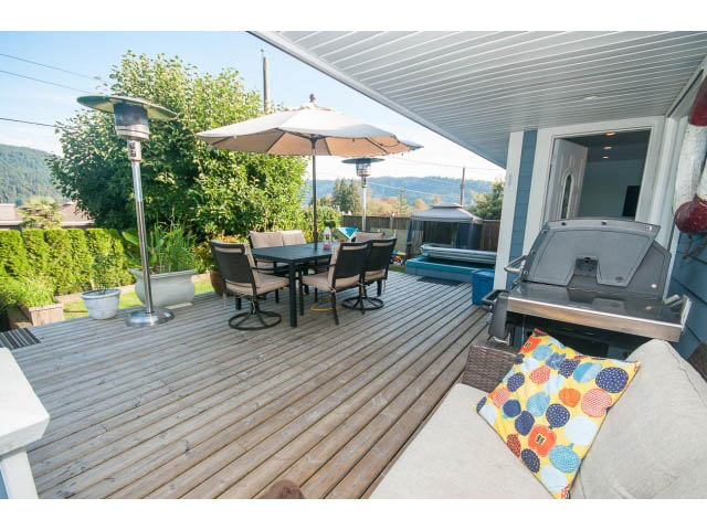 Furnished patio with wooden deck, outdoor furniture, and mountain view. - 389 Beachview Dr, North Vancouver