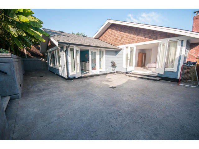 Spacious patio with concrete flooring and sliding glass doors leading to the house. - 389 Beachview Dr, North Vancouver