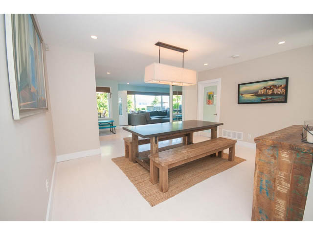 Furnished dining area with wooden table and modern pendant light, leading to a balcony with city view. - 389 Beachview Dr, North Vancouver