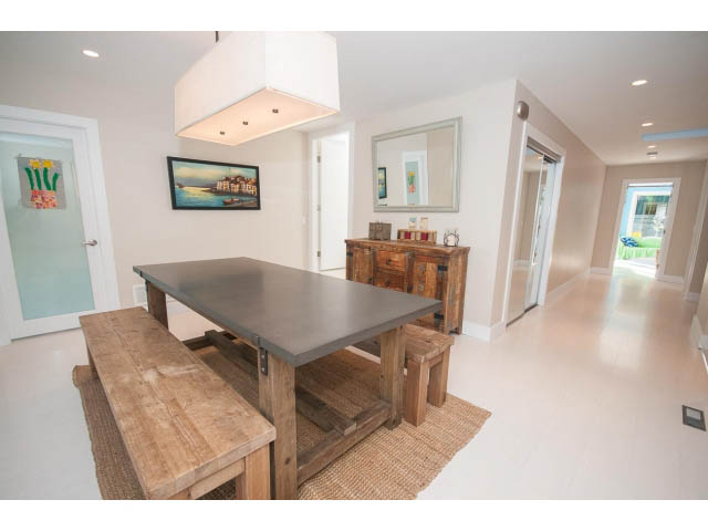 Bright dining area with wooden tables and chairs, modern light fixture, and city view. - 389 Beachview Dr, North Vancouver