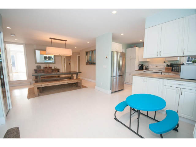 Bright kitchen with white cabinets, stainless steel appliances, and a blue bar stool. - 389 Beachview Dr, North Vancouver
