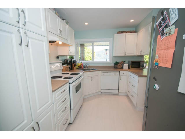 Bright kitchen with white cabinets, hardwood floors, and a window view. - 389 Beachview Dr, North Vancouver