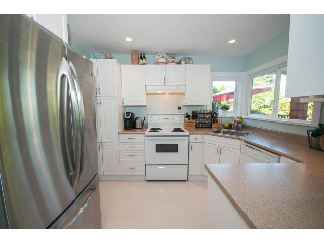 Bright kitchen with white cabinets, granite countertops, and a view of greenery outside. - 389 Beachview Dr, North Vancouver