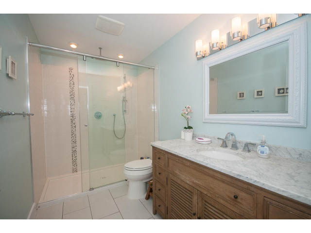 Spacious bathroom with marble countertop and wooden vanity, featuring a walk-in shower. - 389 Beachview Dr, North Vancouver