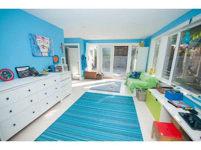 Bright bedroom with blue walls, striped rug, and white dresser. - 389 Beachview Dr, North Vancouver